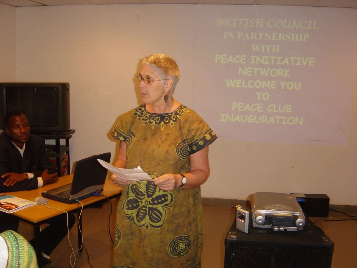A speaker addresses guests at the Peace Club inauguration, with a projected welcome from the British Council and Peace Initiative Network