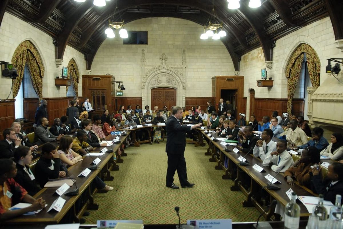 Young people from several countries seated around tables in a committee room at the Houses of Parliament
