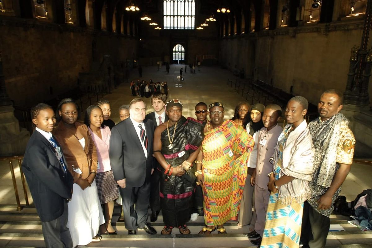 Group of young delegates and guests in traditional and formal dress on the steps of Westminster Hall